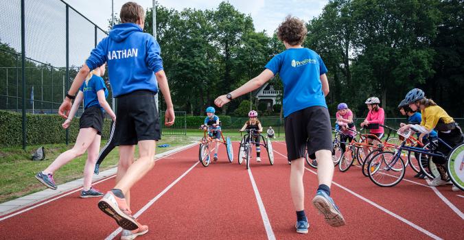 kinderen op een runningframe krijgen les van hun trainers | Inclusieve atletiekverenigingen