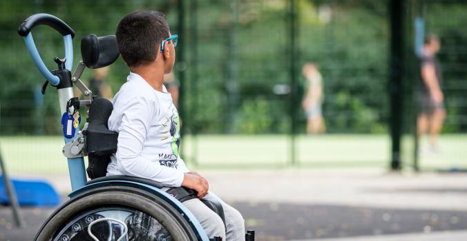 Jayden zit in een rolstoel en kijkt naar spelende kinderen