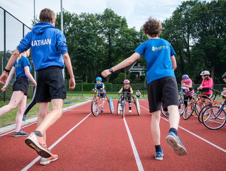 kinderen op een runningframe krijgen les van hun trainers | Inclusieve atletiekverenigingen